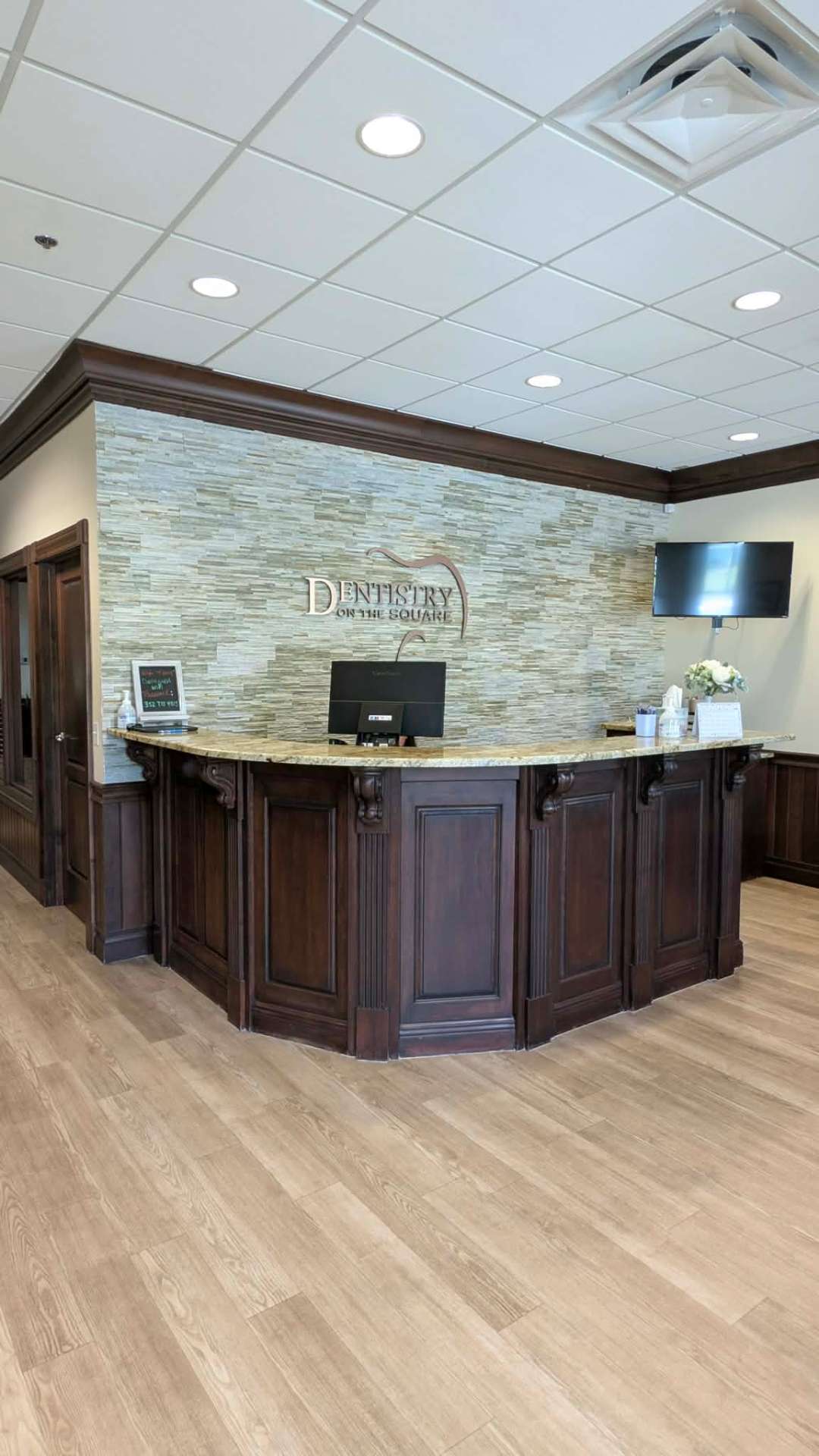 Walnut reception desk with stone feature wall and the Dentistry on the Square logo